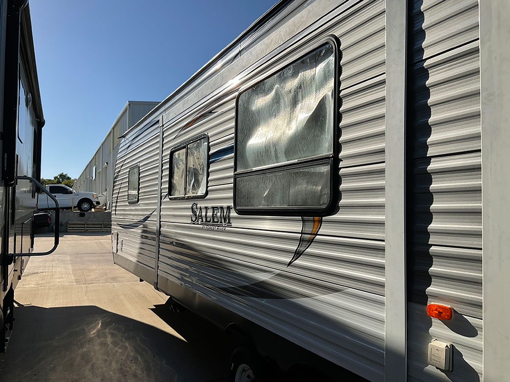 rv travel trailer with damaged siding and windows