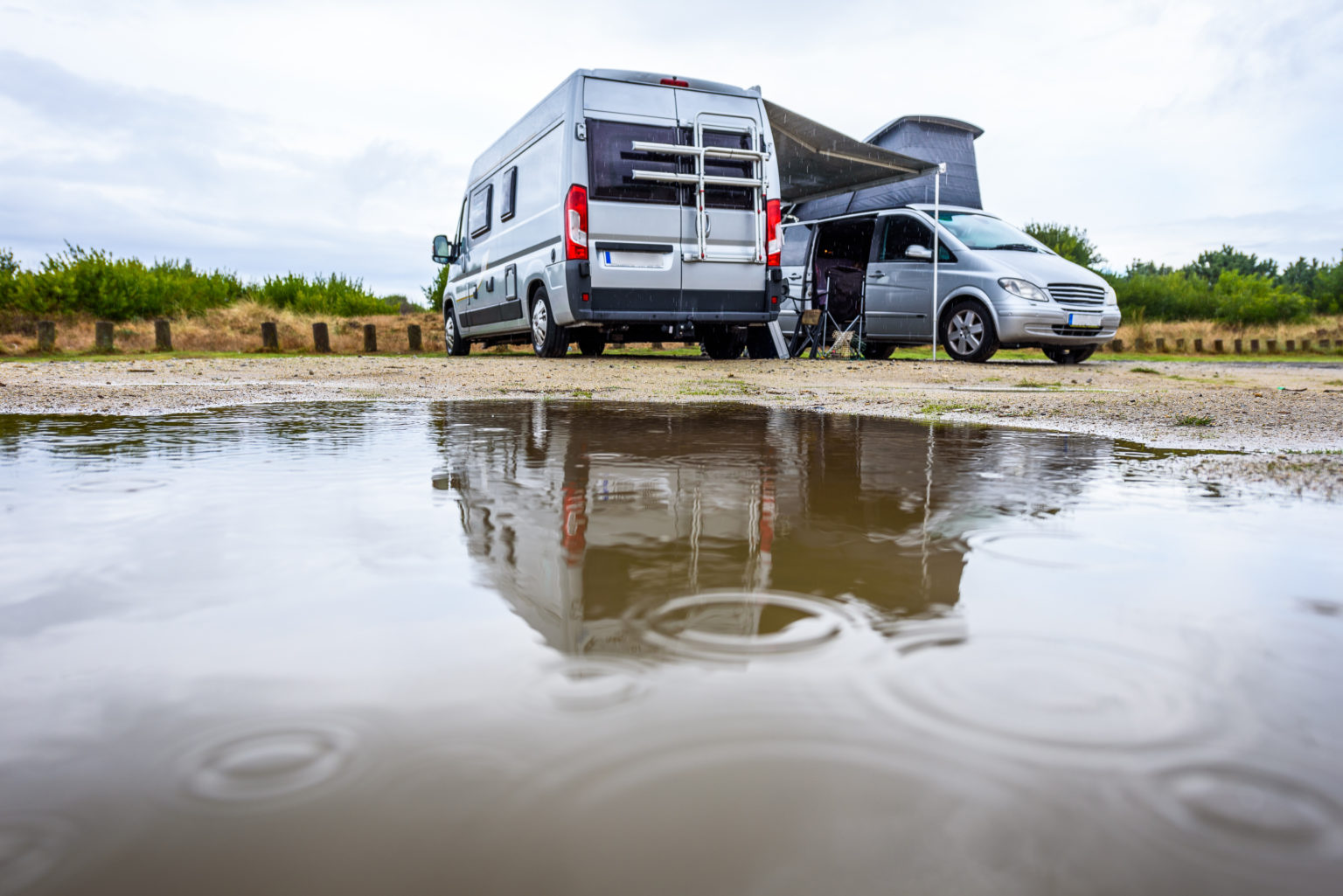 two camper vans parked next to each other in the rain
