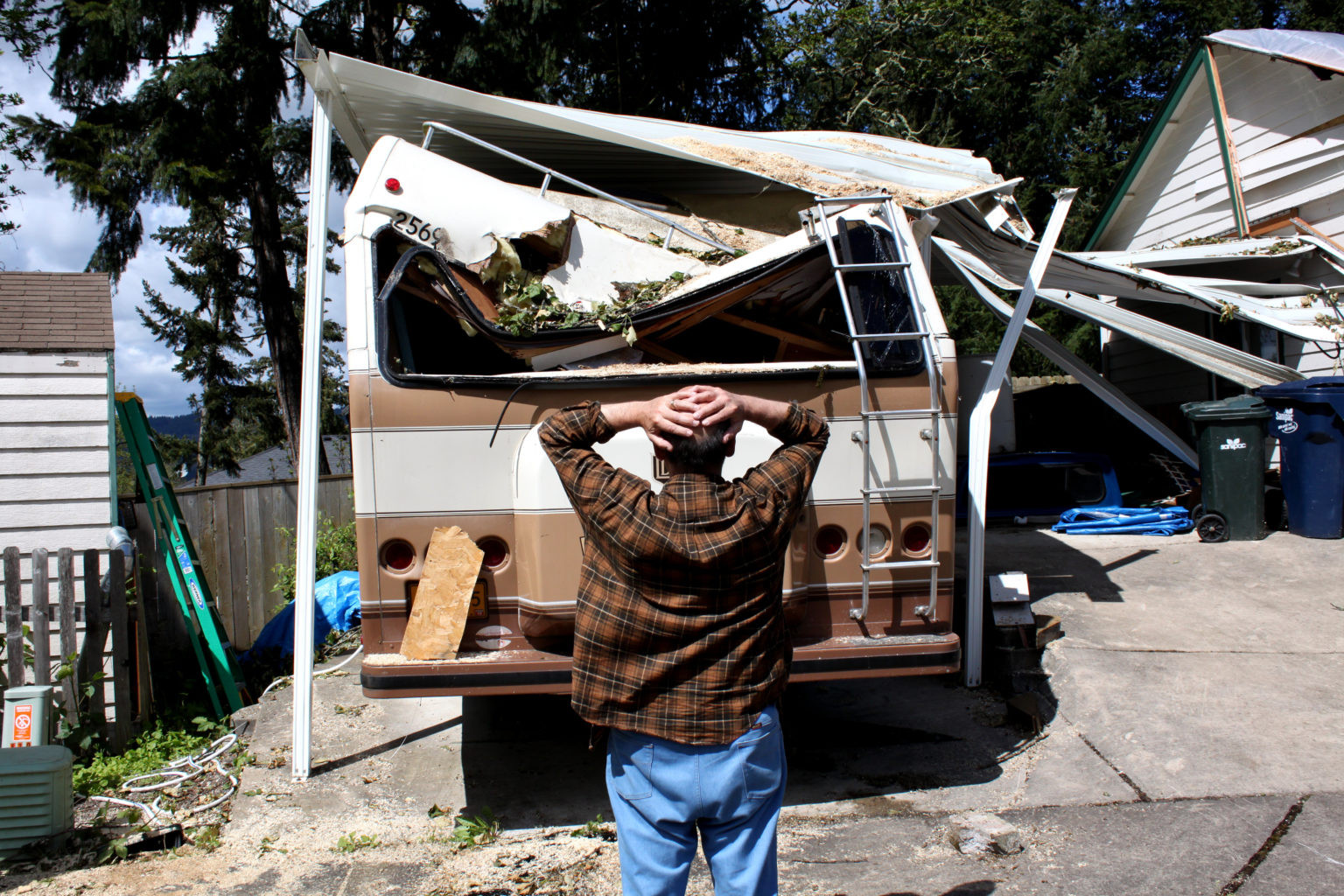 man looking at his rv with severe roof damage